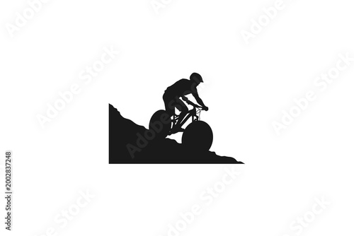 Mountain biker silhouette riding a bicycle down a steep rocky hill
