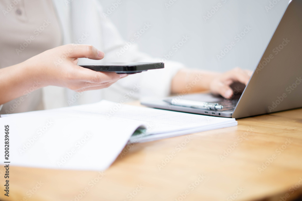 Fototapeta premium Businesswoman Using Smartphone While Reviewing Documents at Desk