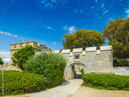 Stone castle walls and an open arched entrance under a sunny blue sky (Portland, England, United Kingdom)