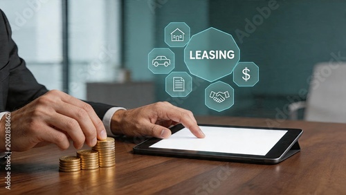 Businessman using tablet with leasing hologram icons showing housecardollar sign and handshake while stacking gold coins on wooden desk in office for finance investment plan