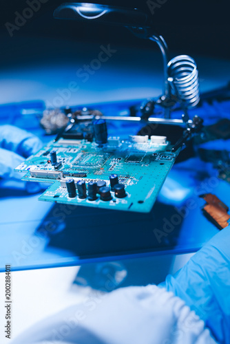 Hands in white gloves carefully repair a broken mobile device, meticulously working on the intricate internal electronics and circuit board