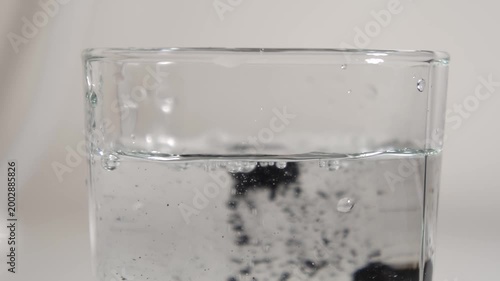 Medicinal pills. Glass of water. Black medical pills. Slow motion. High quality 4k footage