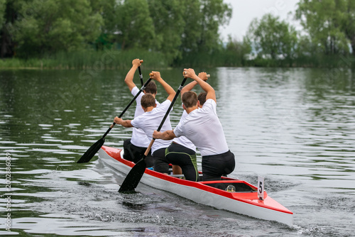 Foto Rear view four athletes canoeist paddling on open water