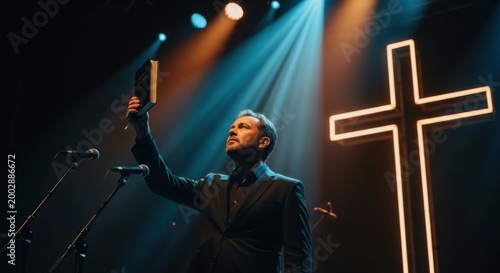 Man holding a book standing on stage with a cross in the background during a religious event