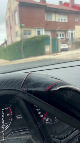 Driver's hands on steering wheel driving through a quiet residential neighborhood