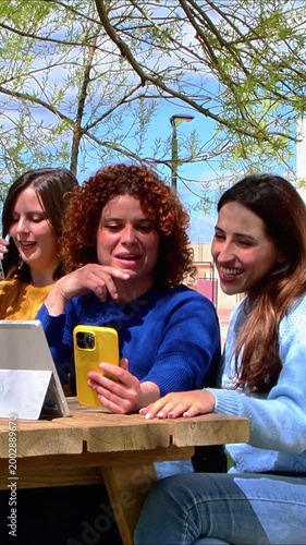 University students studying together using a smartphone and tablet in a campus park
