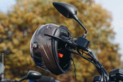 brown motorcycle helmet hanging on black motorcycle handle, safety on road concept