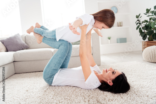 Bild auf Leinwand Mother playing with daughter on the living room carpet, joyful family bonding an