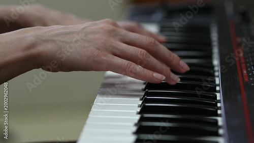 female pianist hands on black and white synthesizer keyboard, close-up view, young woman playing piano, professional musician