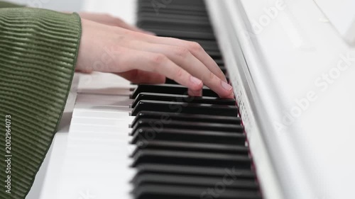 female pianist hands on black and white synthesizer keyboard, close-up view, young woman playing piano, professional musician