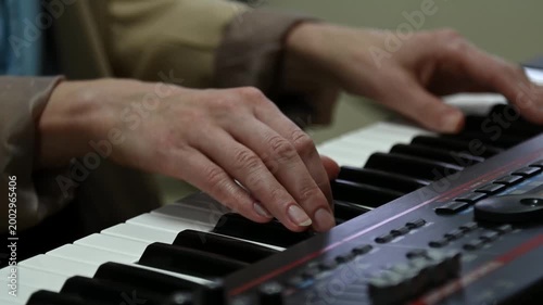 female pianist hands on black and white synthesizer keyboard, close-up view, young woman playing piano, professional musician