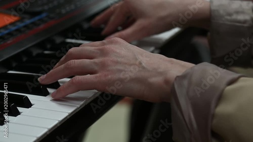 female pianist hands on black and white synthesizer keyboard, close-up view, young woman playing piano, professional musician