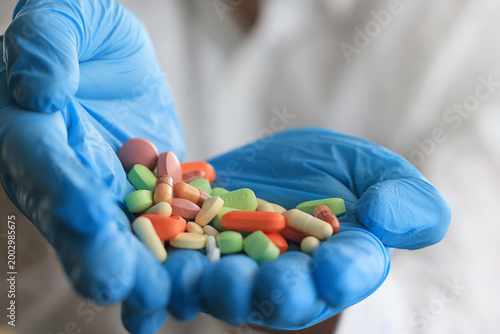 bunch of different pills in the hands of a doctor in blue gloves close-up background pharmacy