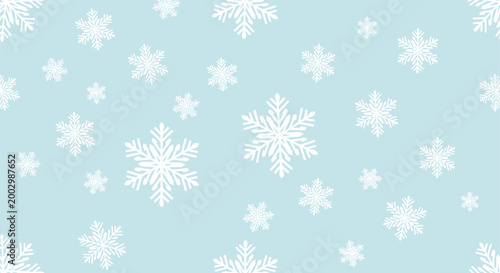 Seamless pattern with white snowflakes of various shapes and sizes on a light blue background for winter and Christmas textiles.