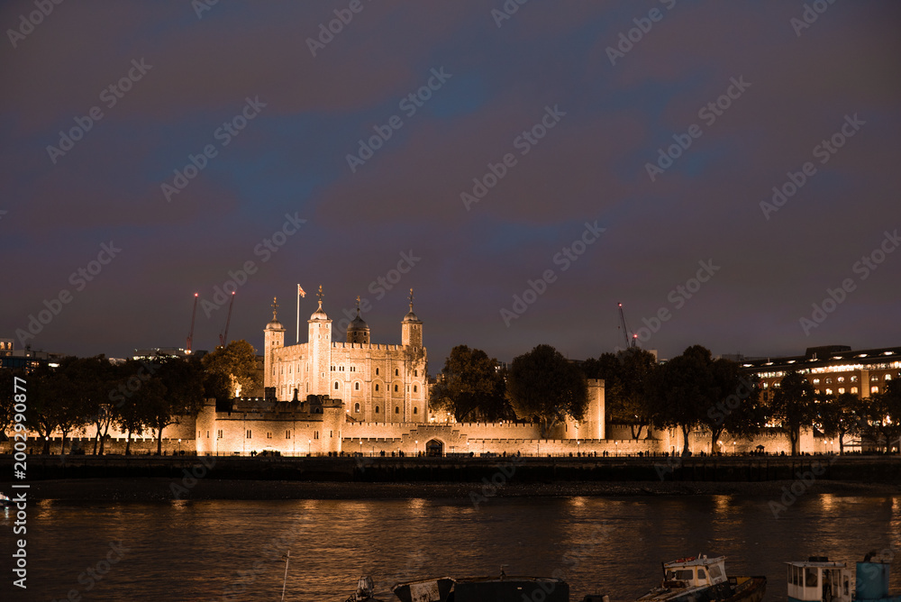 Fototapeta premium Tower of london illuminating thames river at night
