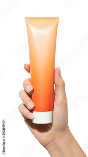 Hand holding orange tube cream isolated on transparent background