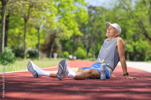 Cuadro en lienzo Elderly man resting on a running track