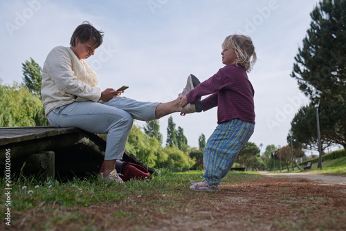 Seeking Attention: Toddler Girl Trying to Distract Her Mother from Smartphone in the Park