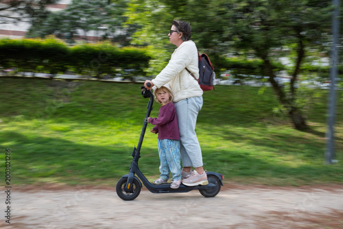 Bilde på lerret Unsafe Journey: Mother and Child Sharing an Electric Scooter at Speed on a City
