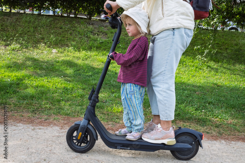 Foto Unsafe Journey: Mother and Child Sharing an Electric Scooter at Speed on a City