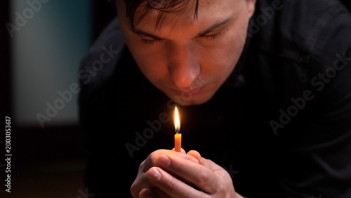Εκτύπωση καμβά Person holding a burning yellow candle in cupped hands, concentrating in prayer