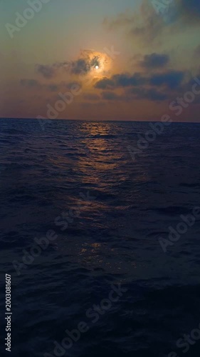 Golden sunset over the open ocean with dramatic clouds and gentle waves