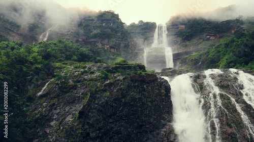 Kynrem Waterfall cascading down towering cliffs through mist and rainforest in Meghalaya India