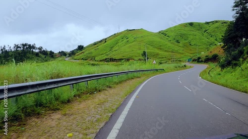 Meghalaya monsoon with road Winding Through Lush Green Mountains, Scenic Road Trip Journey with Rolling Hills and Guardrail Under Overcast Sky