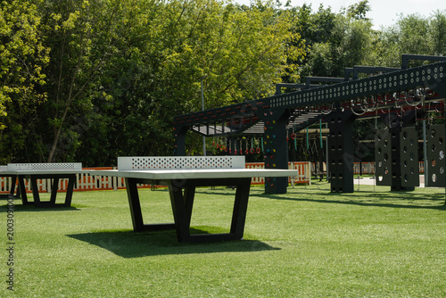 Modern outdoor sports area with table tennis tables and obstacle course equipment in green park, active lifestyle and urban fitness concept