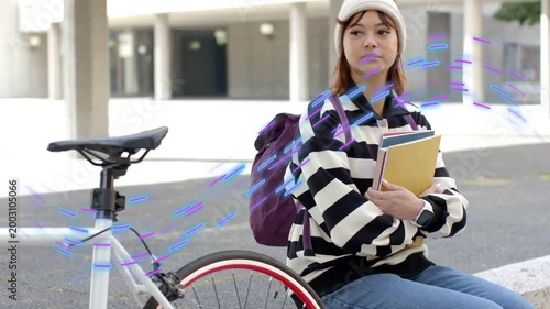 Student sitting by bike with books waiting as camera tightening showing purple streaks across her