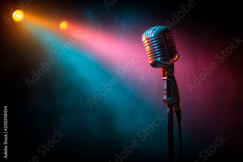 Vintage microphone illuminated by colorful stage lights in a dark setting, creating a vibrant atmosphere ideal for karaoke night or musical performances