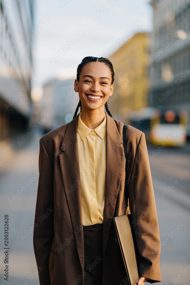 Obraz premium Young professional woman smiling on city sidewalk during daytime