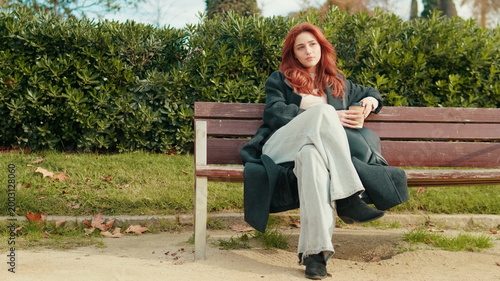 Red-Haired Woman Relaxing On Park Bench With Coffee