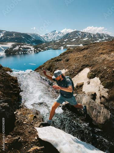 Man hiking solo in Norway travel trail running adventure in the great outdoors - active hiker traveler crossing river in Lahko park, healthy lifestyle summer vacations endurance energy freedom concept