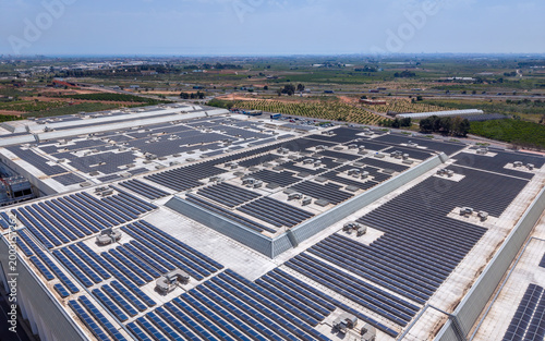 Schilderij op canvas Aerial view of massive solar panel array covering entire rooftop of large indust