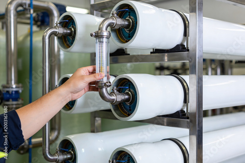 Fotografi Technician inspecting industrial water filtration system with flow meter and mem
