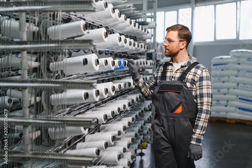Bild auf Leinwand Worker controlling polypropylene thread spools in a textile factory