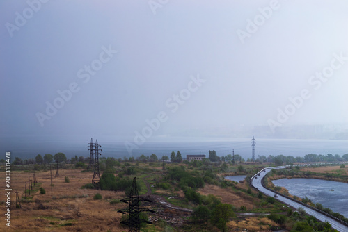 Rainstorm over lake and industrial cityscape