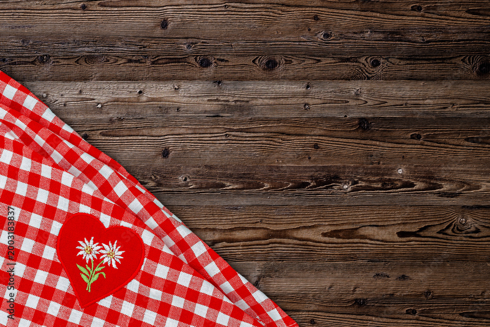 Obraz premium Red checkered tablecloth with floral heart patch placed on wooden table at a gathering in the afternoon