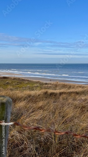 Ocean horizon, vertical image of the coastal Dutch landscape of the dunes and the beach along the blue waters of the North Sea outdoor at daytime during springtime season in Noordwijk aan Zee, Holland
