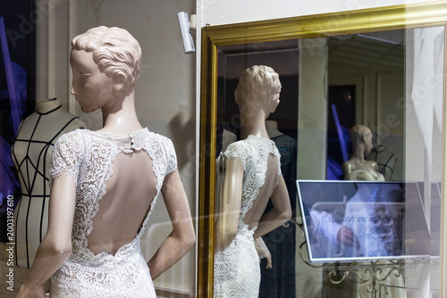 Shop window display with wedding dress, sophisticated bridal couture, lace embroidery, mannequin pose, retail fashion