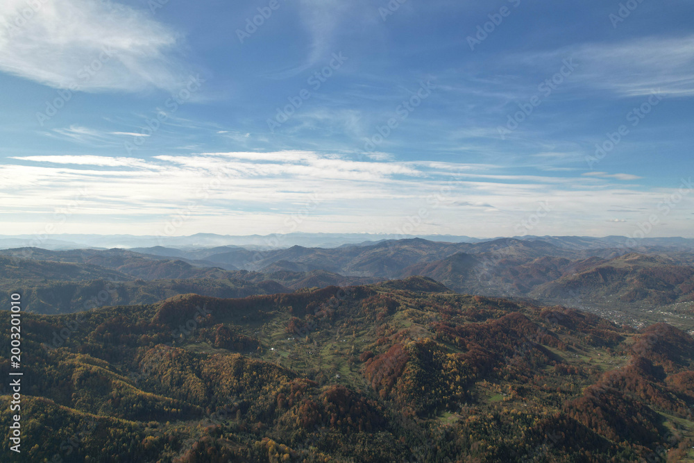 Fototapeta premium High angle aerial view of autumn mountain ridges under blue sky