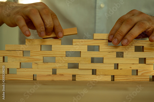Close up of hands carefully placing wooden blocks to create a structure