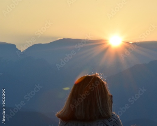 Tableau sur toile Scenic mountain landscape at sunrise with warm golden sunlight, layered mountain ridges, and silhouette of a person enjoying the peaceful natural view