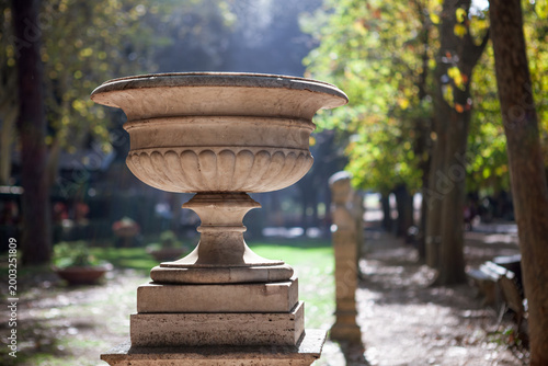 Close-up of a decorative stone urn under bright sunlight in the gardens of Villa Borghese.