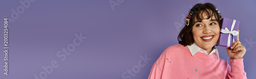 Fotografie Stylish young woman expressing joy while holding a vibrant gift against a colorf