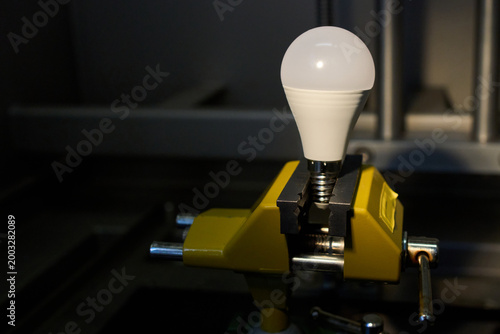 Картината върху платно LED light bulb clamped in a yellow metal vise