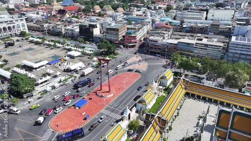 The red GiantSwing and wat suthat thepwararam temple appear within active city streets, historic architecture and movement around.