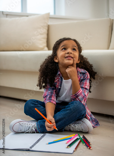 Girl thinking while drawing at home.