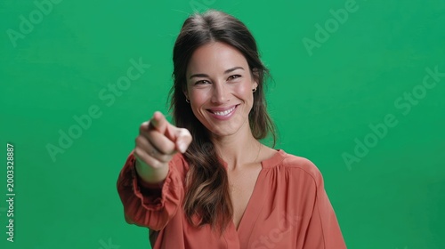 Confident Pointer: A woman exudes confidence as she points directly towards the viewer with a knowing smile, set against a vibrant green backdrop, making an unmistakable declaration of empowerment.
